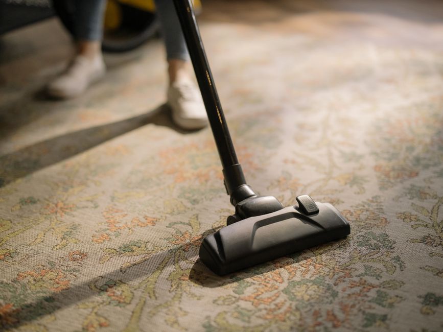 Professional cleaner thoroughly vacuuming a carpet